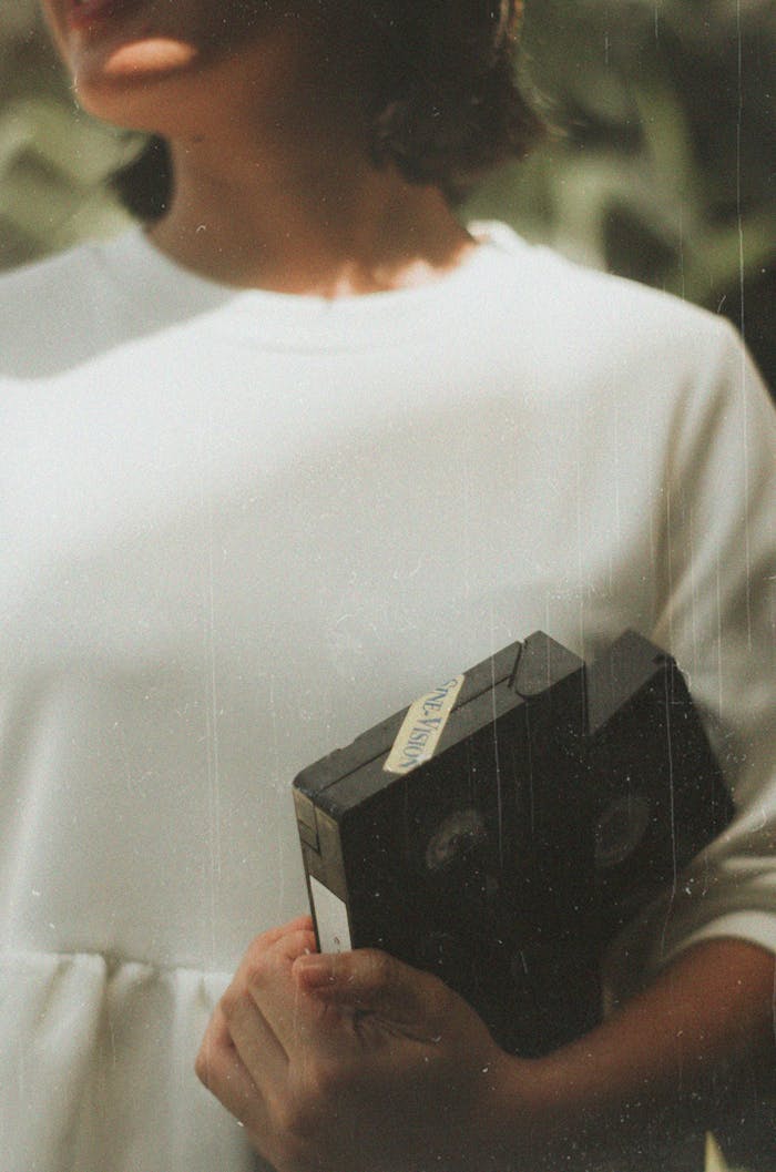 service-03 A woman in vintage style holds VHS tapes, evoking nostalgia.